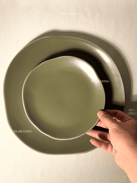 Hand holding the Verdant full plate and quarter plate, showing the matte olive glaze and off-round shape — Lair Living