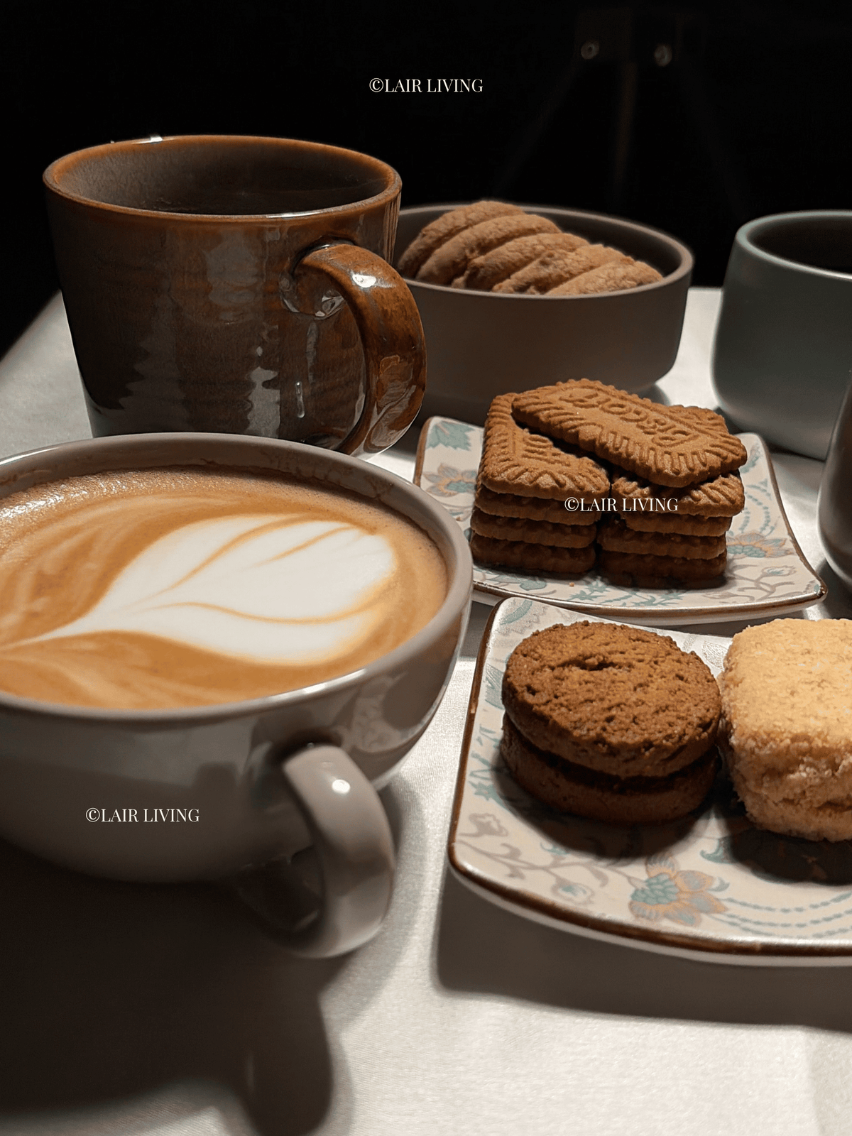 Ashen cappuccino cup filled with a latte and rosetta art, styled with biscuits on a ceramic platter — Lair Living