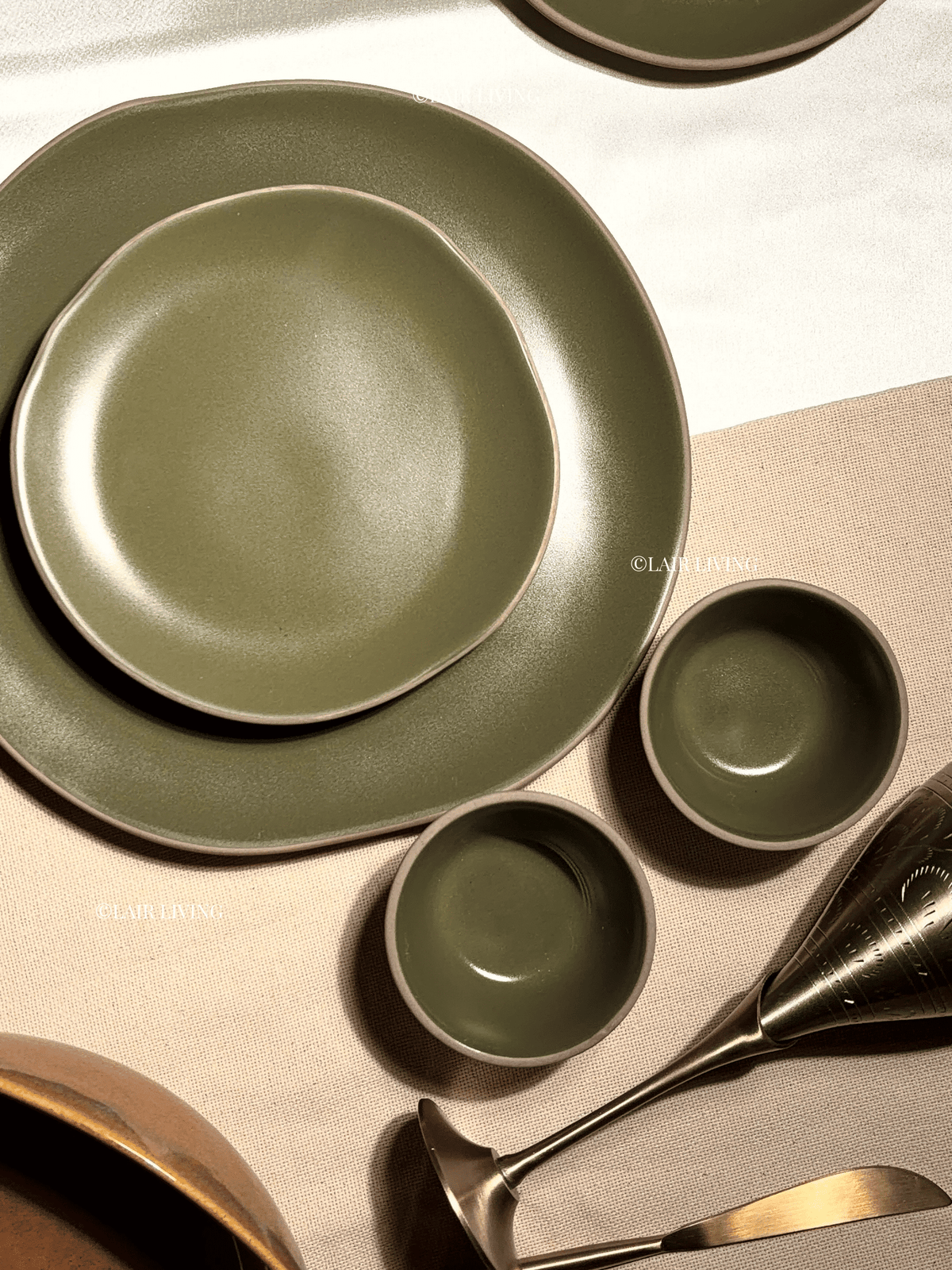 Verdant olive-green dinner plate styled on a linen table with katoris and brass cutlery — Lair Living stoneware