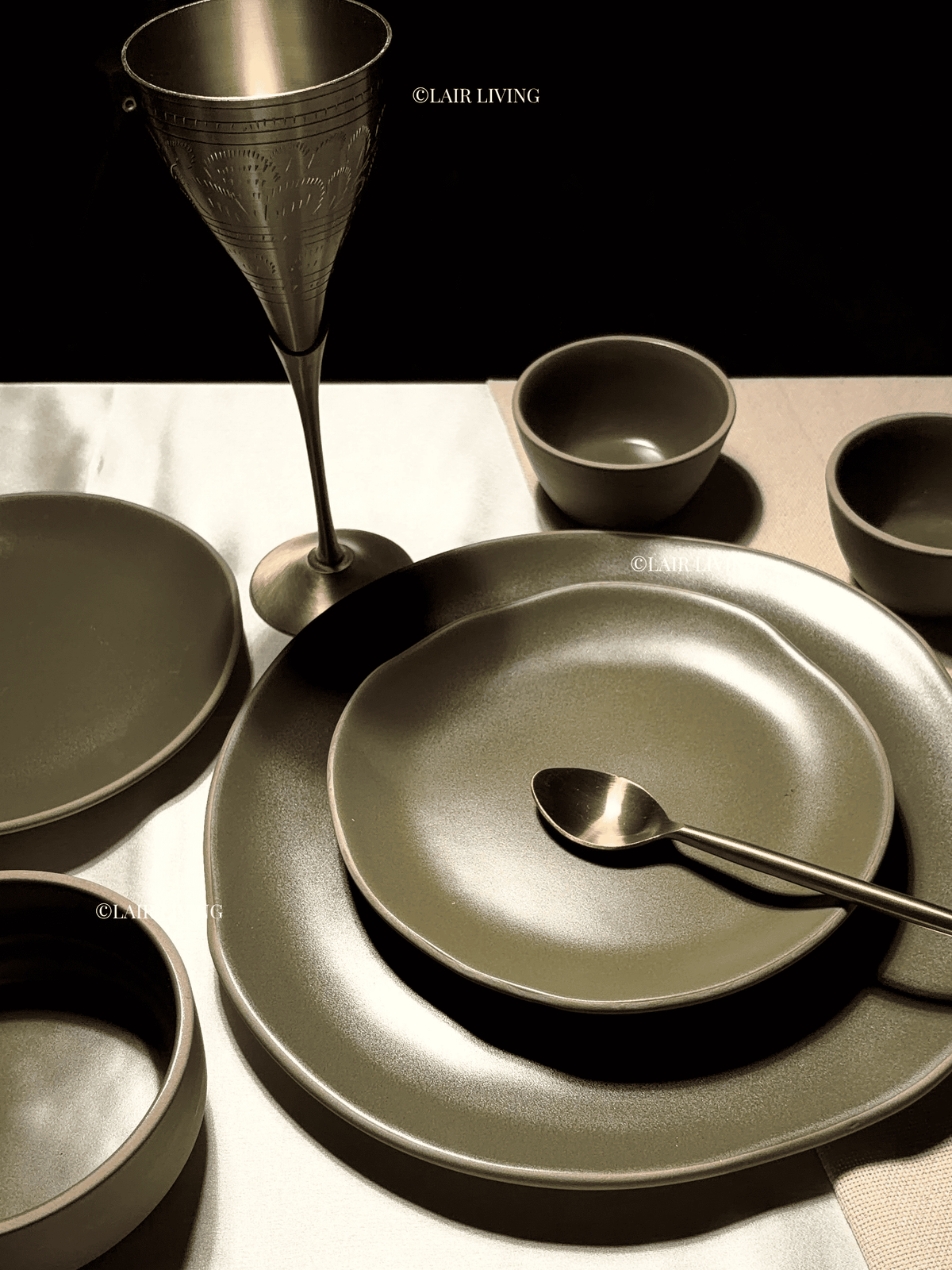 Verdant matte olive place setting with brass goblet and gold spoon on a linen table — Lair Living ceramic